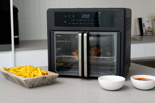 25L Air Fryer Convection Oven with French Doors cooking chicken, fries, and sauces displayed on the counter, advanced air frying technology.