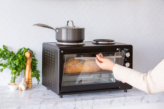 Portable oven with rotisserie cooking a chicken, 34L capacity, 1700W, on a kitchen countertop. Value furniture, affordable, quality appliance.