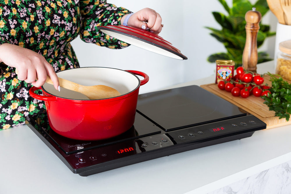 Person using double induction cooker with red pot and wooden spoon in a modern kitchen, highlighting quality and affordable value furniture