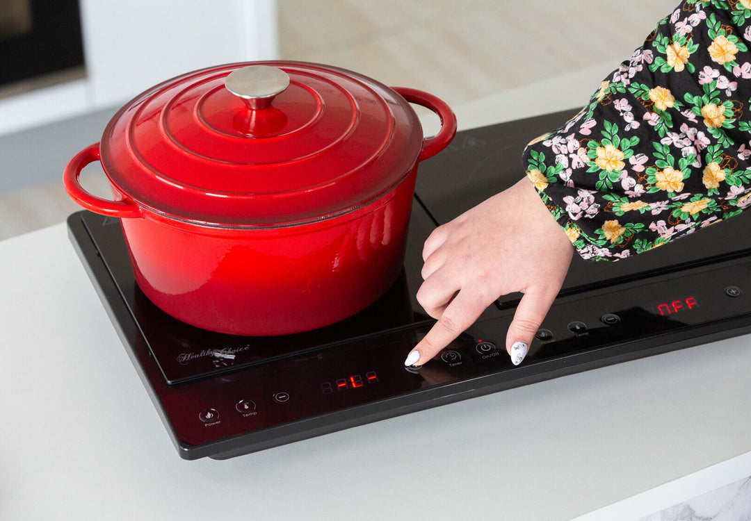 Person adjusting settings on double induction cooker with red pot, digital display, versatile for quality and affordable cooking.