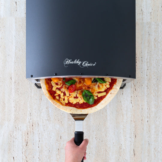 Baking pizza in a compact and portable 12" healthy choice electric oven on a wooden surface.