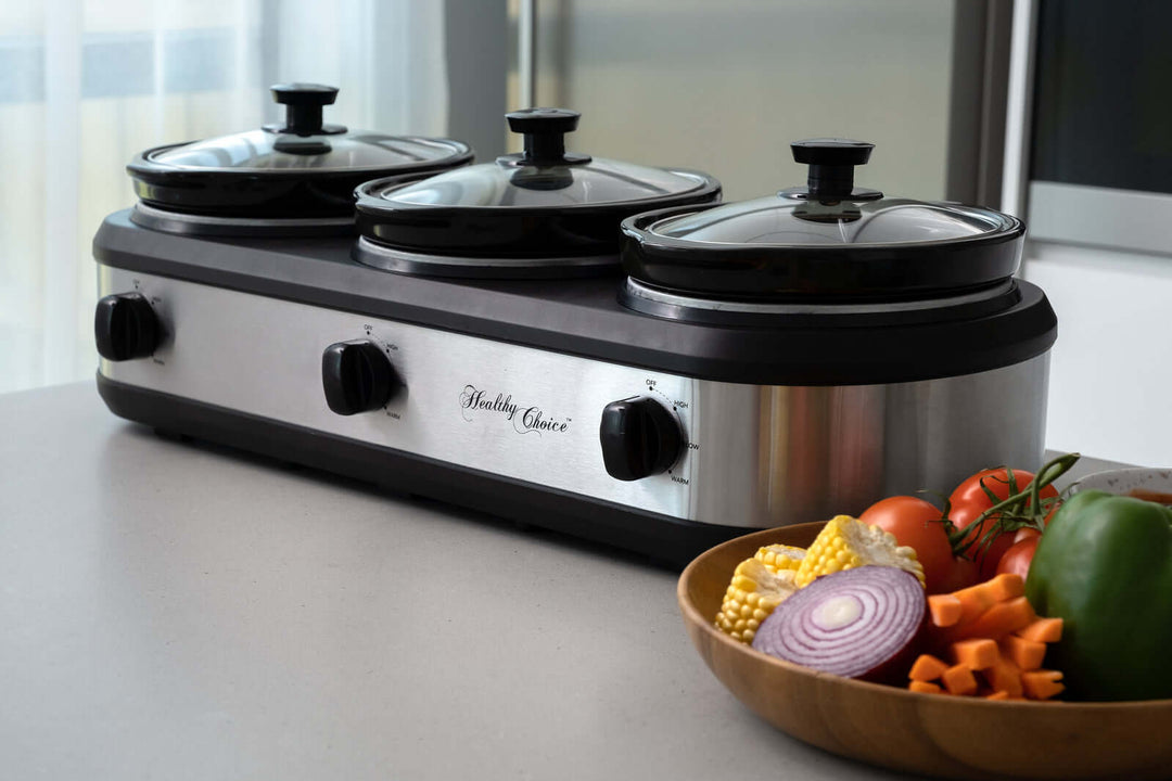 3-Pot Slow Cooker with glass lids, knobs, and fresh vegetables on a countertop for healthy cooking.