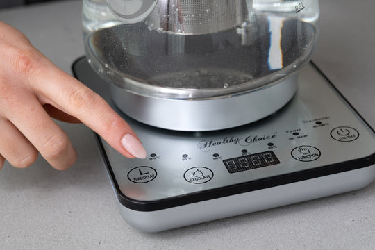 Person using digital controls on 1.2L glass kettle with electric tea pot and infuser, showcasing the quality and affordable value furniture appliance.