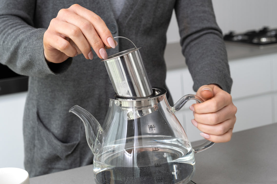 Person using the 1.2L Digital Glass Kettle with Electric Tea Pot & Infuser in a modern kitchen, highlighting value furniture, affordable quality.