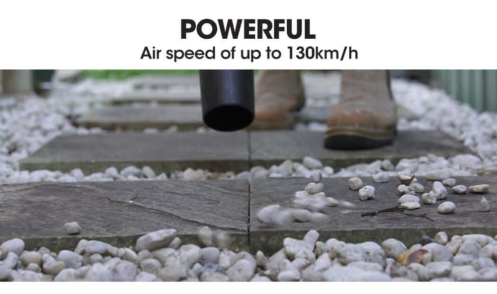 Powerful handheld leaf blower with air speed up to 130km/h clearing pebbles from stone path.