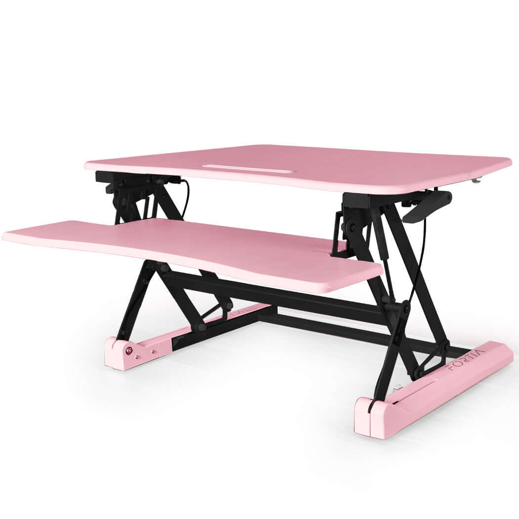 Pink adjustable sit-stand desk riser for dual monitors, ergonomically designed for home office use.