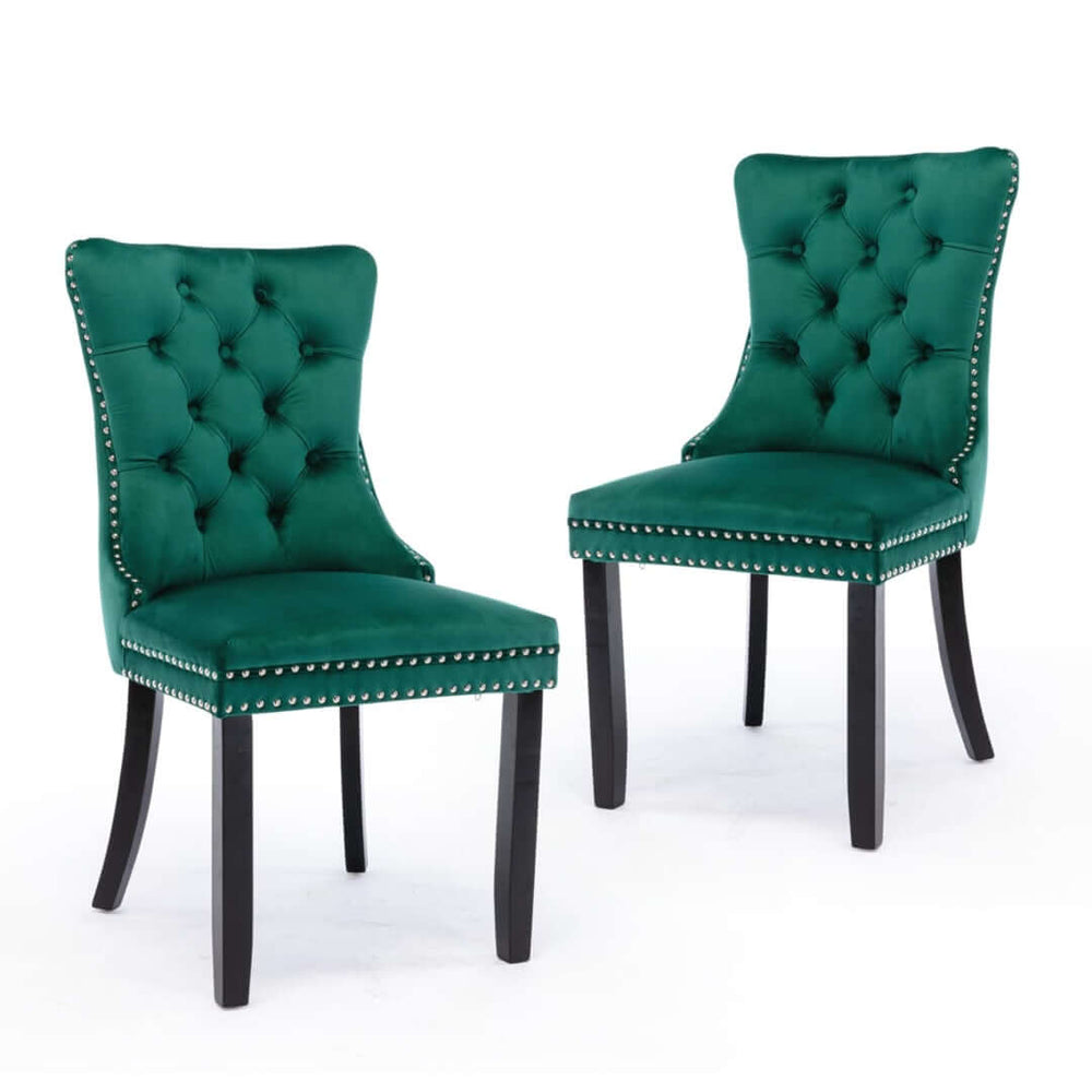 Set of 2 green velvet dining chairs with tufted backs, solid wood legs, and studded trim for a modern, luxurious look.