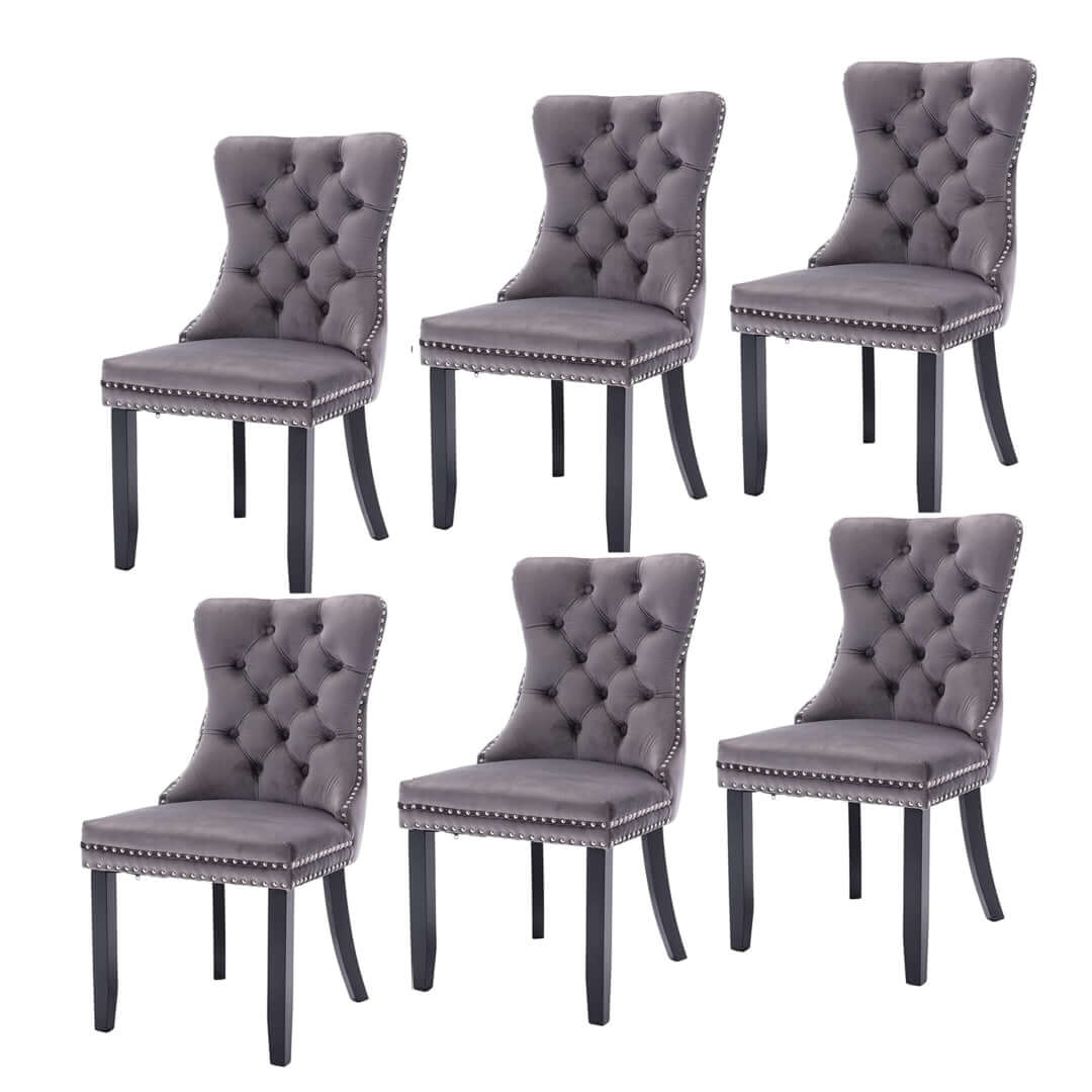 6x gray velvet dining chairs with tufted upholstery, solid wood legs, stud trim, and ring accents displaying modern mid-century style.