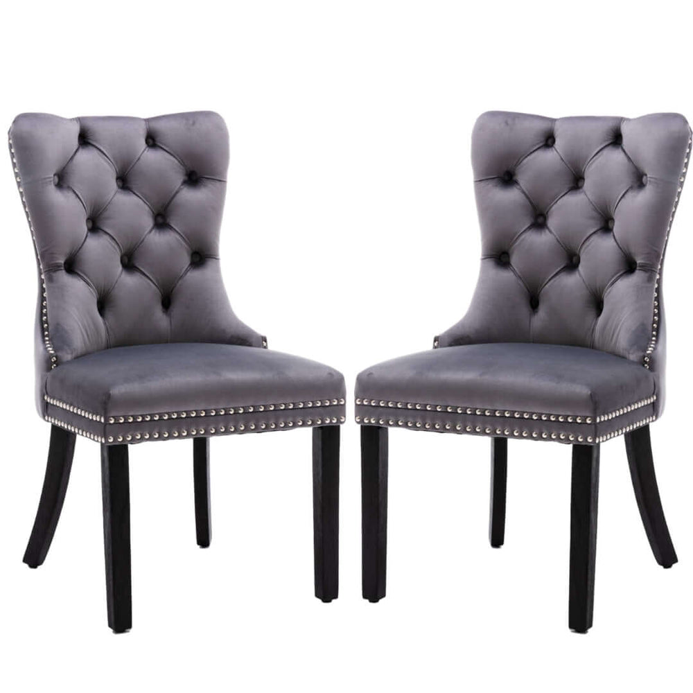 Gray velvet dining chairs with deep tufted back, solid wood legs, and stud trim detailing