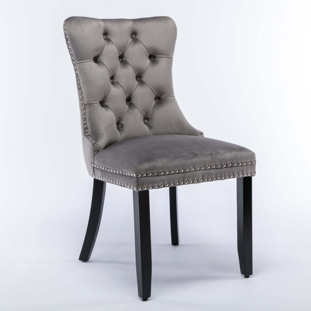 Gray velvet dining chair with tufted back, stud trim, and solid wood legs for a modern mid-century look.