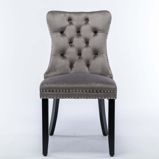 Gray velvet tufted dining chair with solid wood legs and stud trim, featuring a high back and contemporary design.