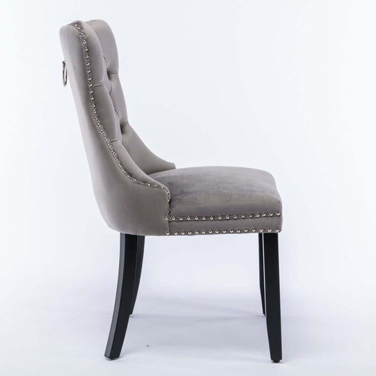 Side view of gray velvet dining chair with tufted back, solid wood legs, and stud trim detailing.