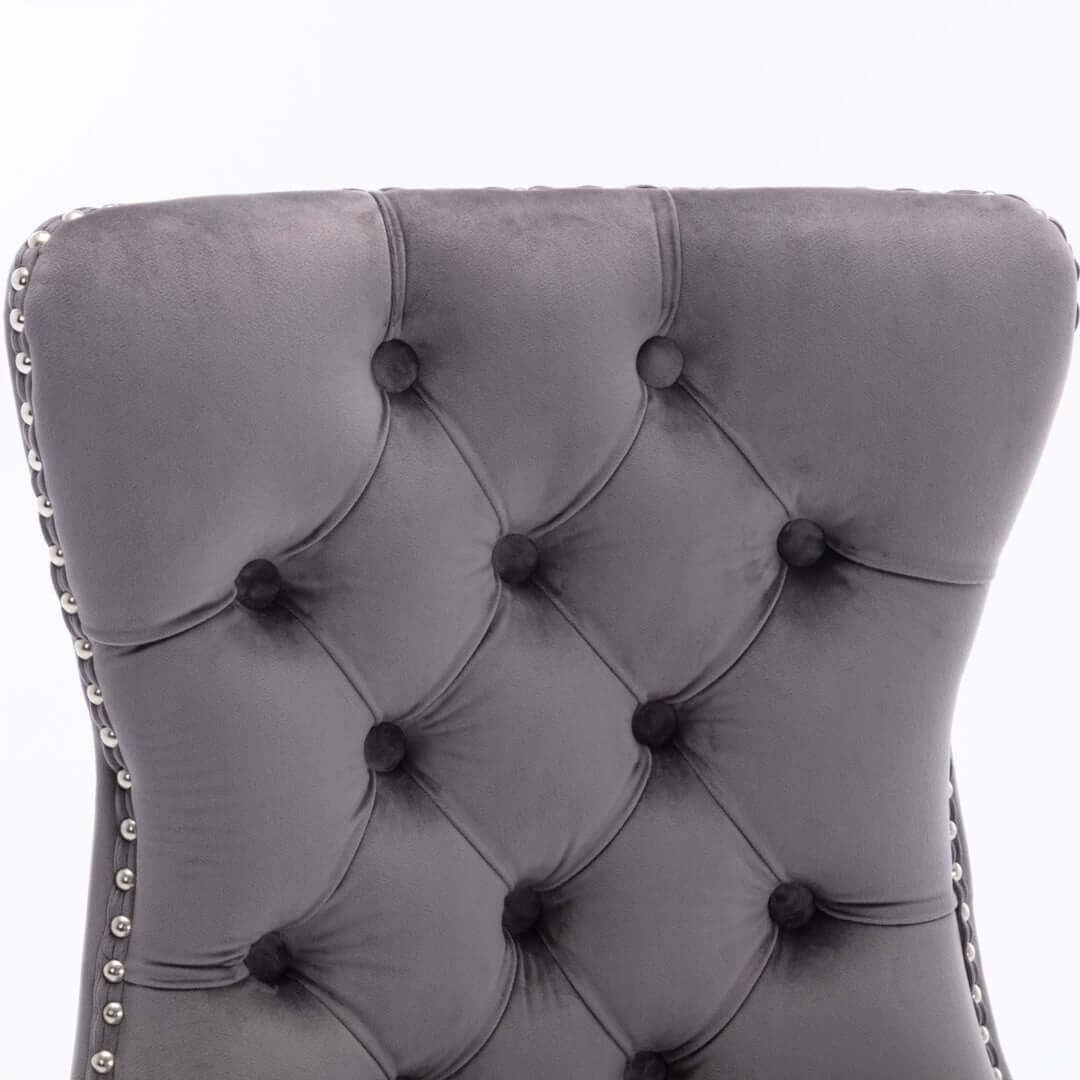 Close-up of tufted velvet backrest with stud trim on gray upholstered dining chair.