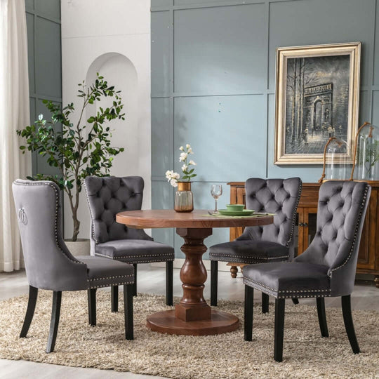 Gray velvet dining chairs with solid wood legs and tufted back around a round wooden table in a contemporary dining room.