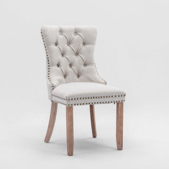 Elegant button-tufted beige dining chair with stud trim and wooden legs, perfect for affordable luxury decor.