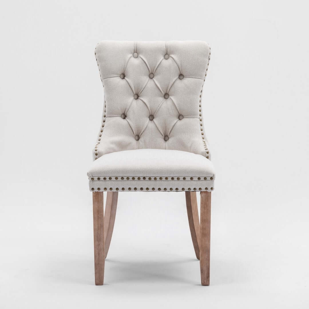 Affordable beige button-tufted dining side chair with stud trim and wooden legs for elegant dining and living spaces.