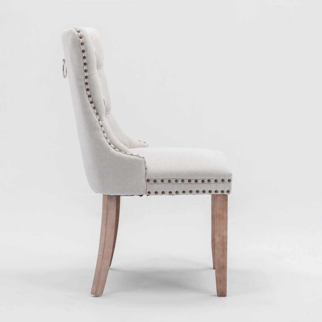 Side view of AADEN modern dining chair with button-tufted upholstery and stud trim, featuring wooden legs.