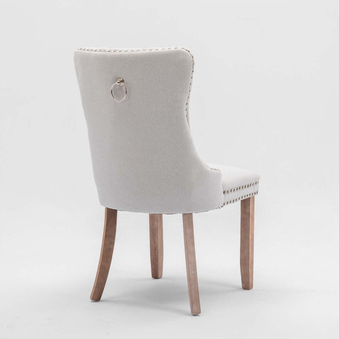 Affordable modern beige dining chair with button-tufted back and stud trim, perfect for elegant dining setups.