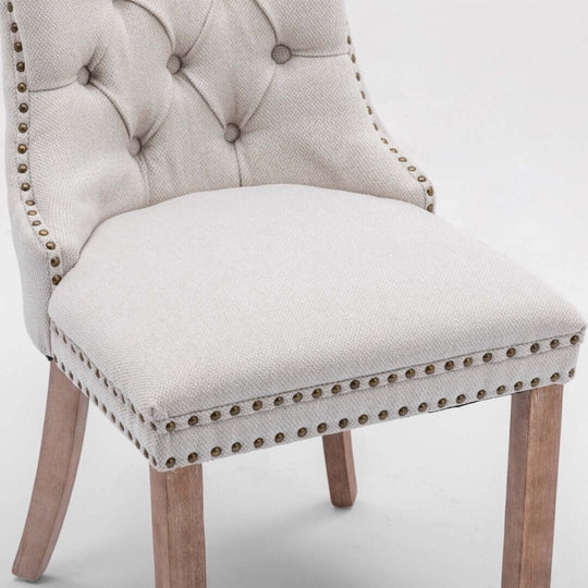 Elegant beige button-tufted upholstered dining chair with stud trim and wooden legs, perfect for affordable luxury.