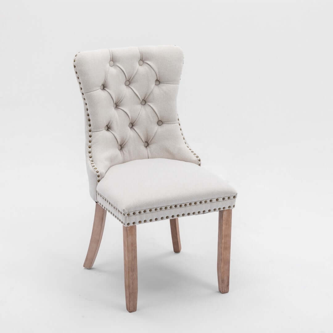 Elegant beige button-tufted dining chair with stud trim and wooden legs, perfect for stylish seating.