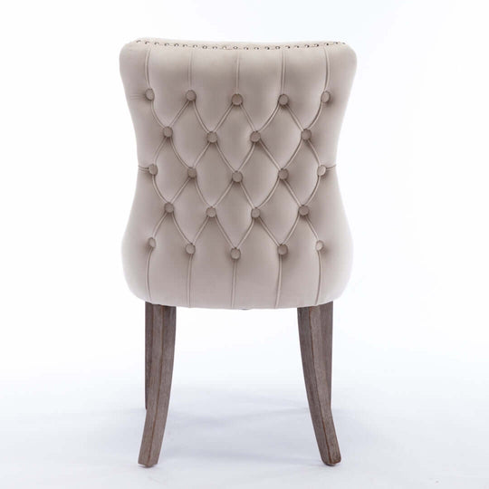 Back view of velvet upholstered tufted wingback side chair with studs trim and solid wood legs for dining or kitchen.