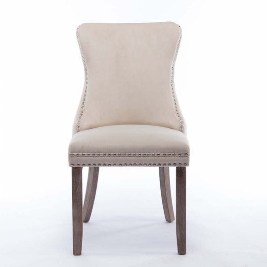 Velvet upholstered dining chair with tufted wingback design, studded trim, and solid wood legs for kitchen and dining room use.