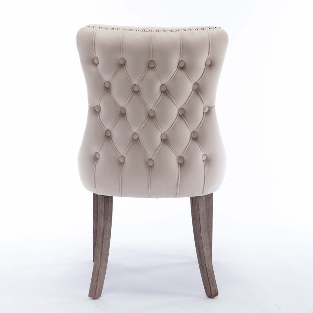 Back view of beige velvet upholstered dining chair with tufted design and solid wood legs