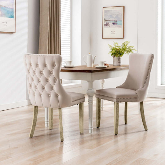 Velvet upholstered tufted wingback dining chairs with solid wood legs at a dining table in a modern kitchen setting