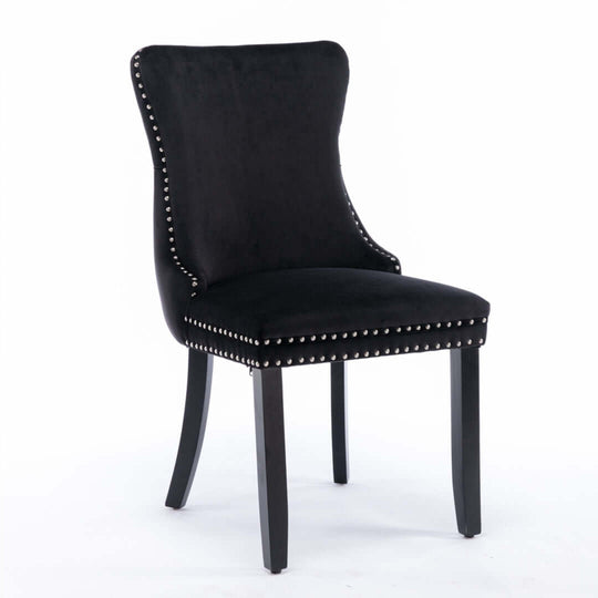 Velvet upholstered black dining chair with studs trim and solid wood legs.