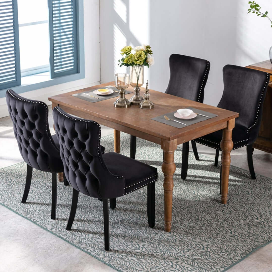 Velvet upholstered tufted dining chairs with stud trim and solid wood legs around a wooden dining table in an elegant modern kitchen setting.