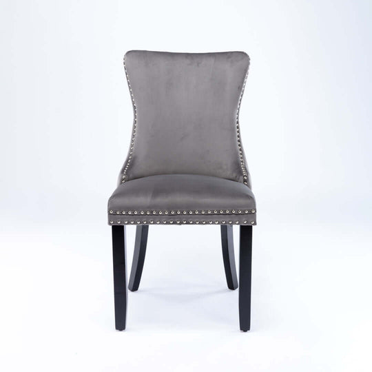 Velvet upholstered dining chair with tufted wingback, stud trim, and solid wood legs in a modern elegant design.