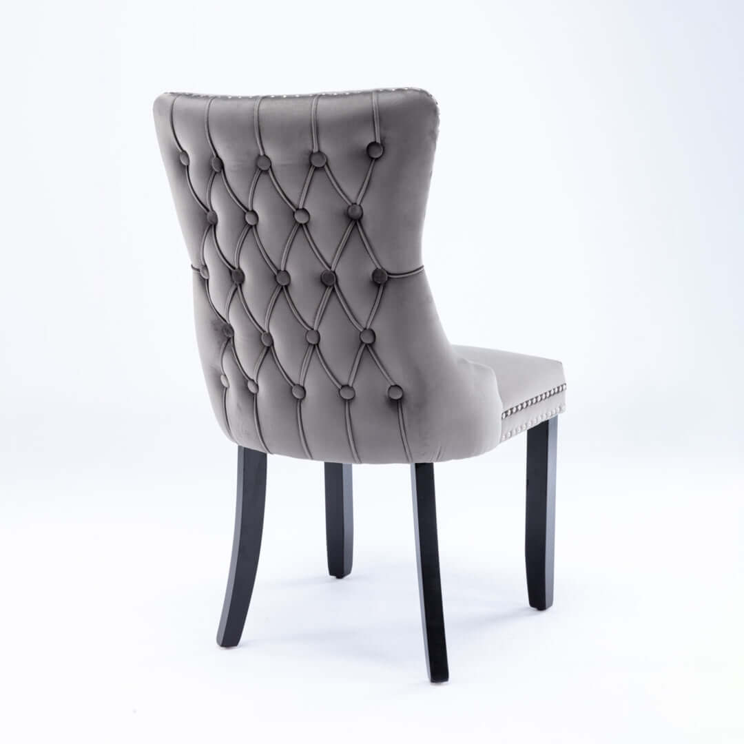 Velvet upholstered dining chair with tufted wingback design and studs trim, solid wood legs, ideal for kitchen or dining room.