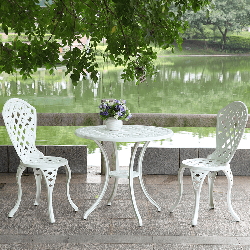 Modern white aluminum 3-piece outdoor set with two chairs and a round table beside a serene lake.