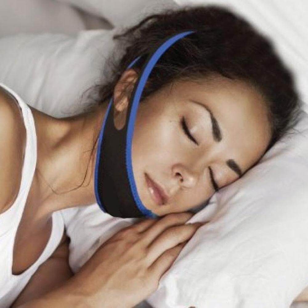 Woman sleeping peacefully with an adjustable anti-snoring chin strap for better sleep quality.