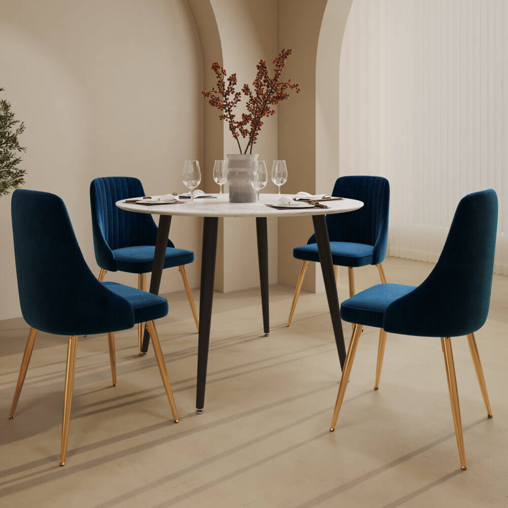 Blue velvet dining chairs and white round table with marble effect in a stylish dining room setup.