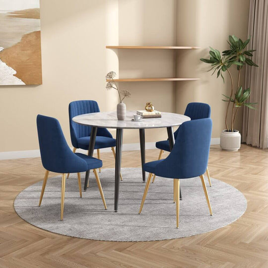 Blue velvet dining set with round marble-effect white table and four chairs in modern styled room.