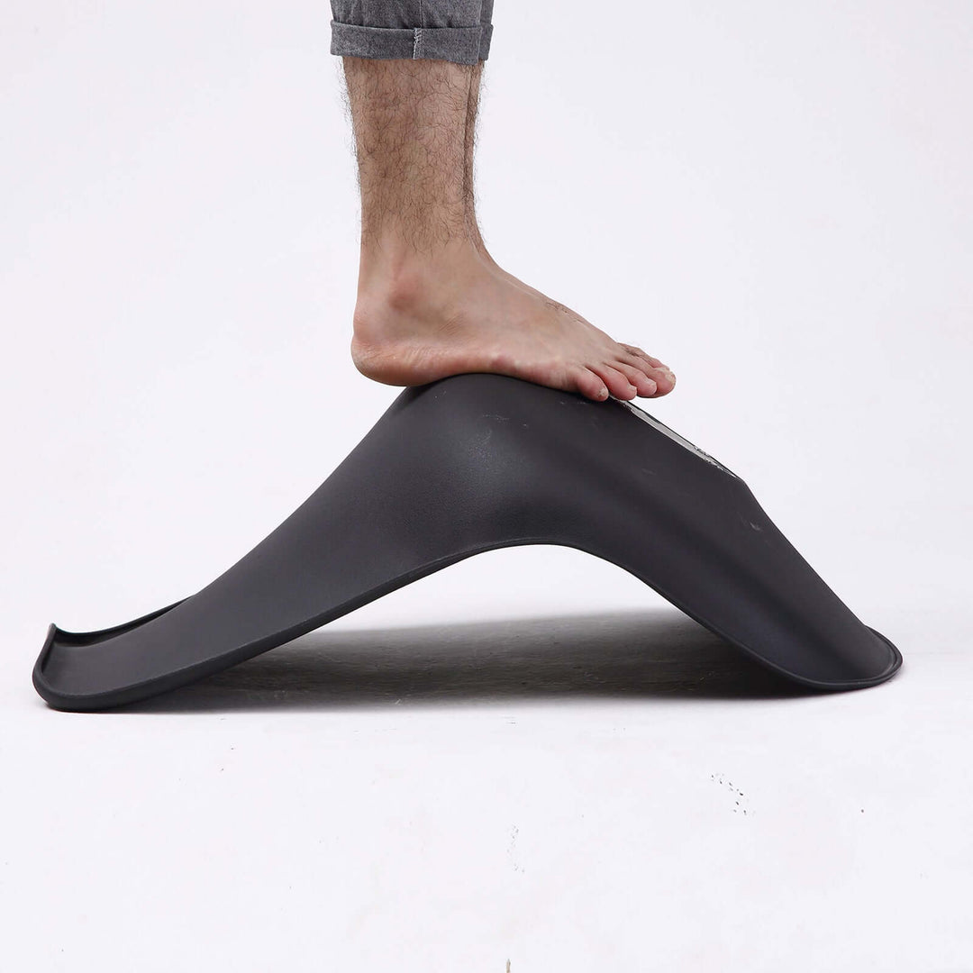 A person stepping on a black ergonomic footrest for optimal support and comfort.