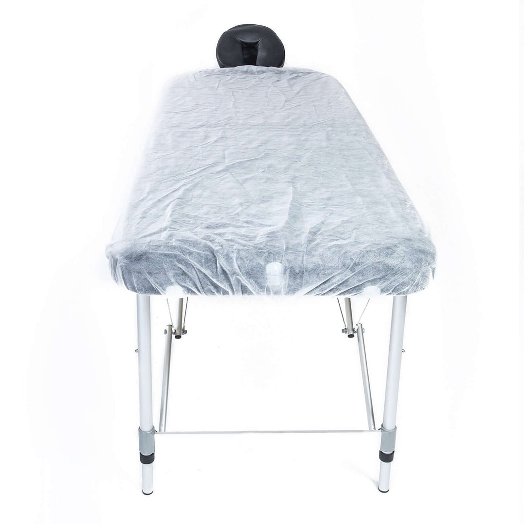 Disposable massage table sheet cover in gray on a foldable table, showcasing affordability and quality for spa services.