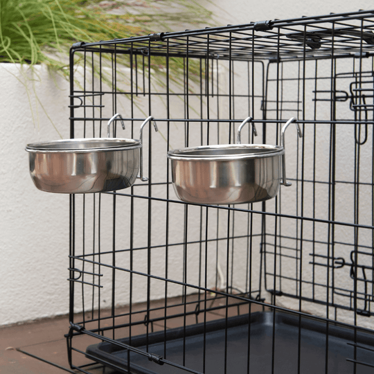 Affordable stainless steel pet food and water bowls securely attached in a wire cage.