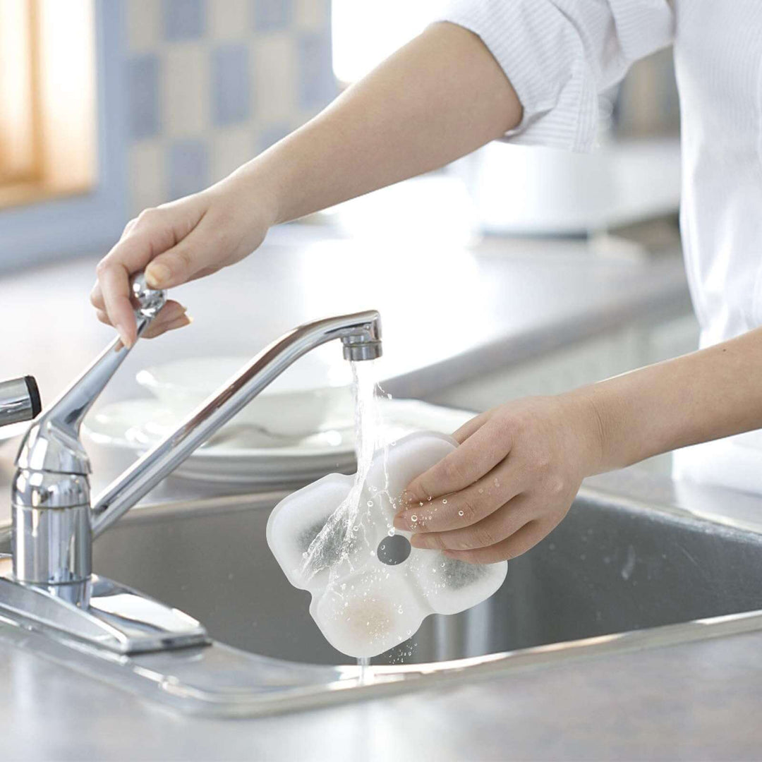 Person rinsing a pet fountain filter under a kitchen faucet for easy cleaning and maintenance.