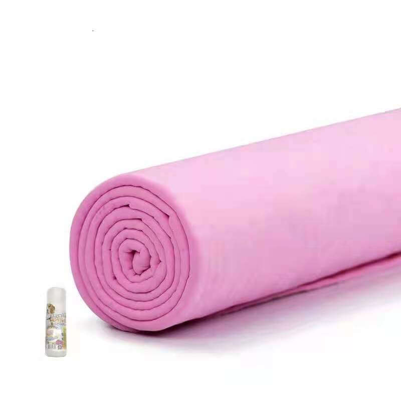 Rolled pink towel next to a small bottle, ideal for pet grooming and drying, soft and absorbent.