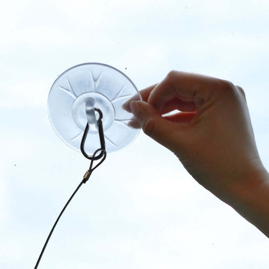 Person attaching a suction cup for a cat window hammock, showcasing easy DIY assembly options.