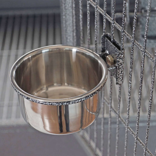 Stainless steel feeder bowl mounted on a bird cage, designed for easy access and cleaning.