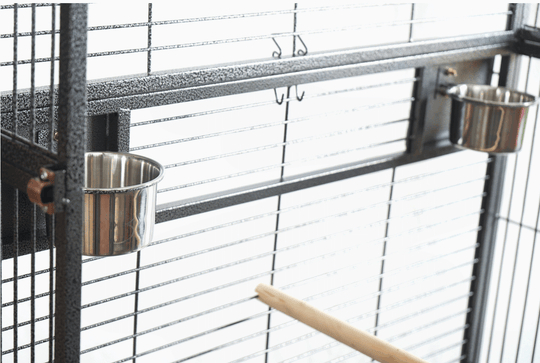 Interior view of YES4PETS aviary cage featuring two stainless steel food bowls and a wooden perch for birds.