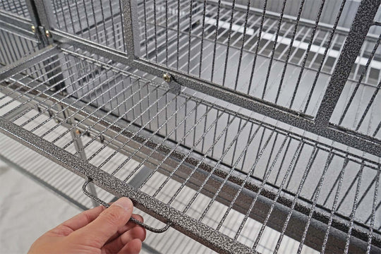 Hand holding the slide-out tray of YES4PETS XL bird cage, showcasing easy cleaning features.