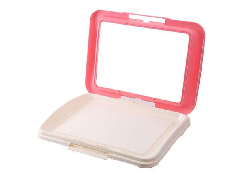 Portable dog potty training tray in pink and white, designed for easy waste removal and hygienic use.