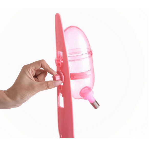 Hand adjusting a pink water and food feeder for dogs, cats, and small pets, highlighting its practicality and design.