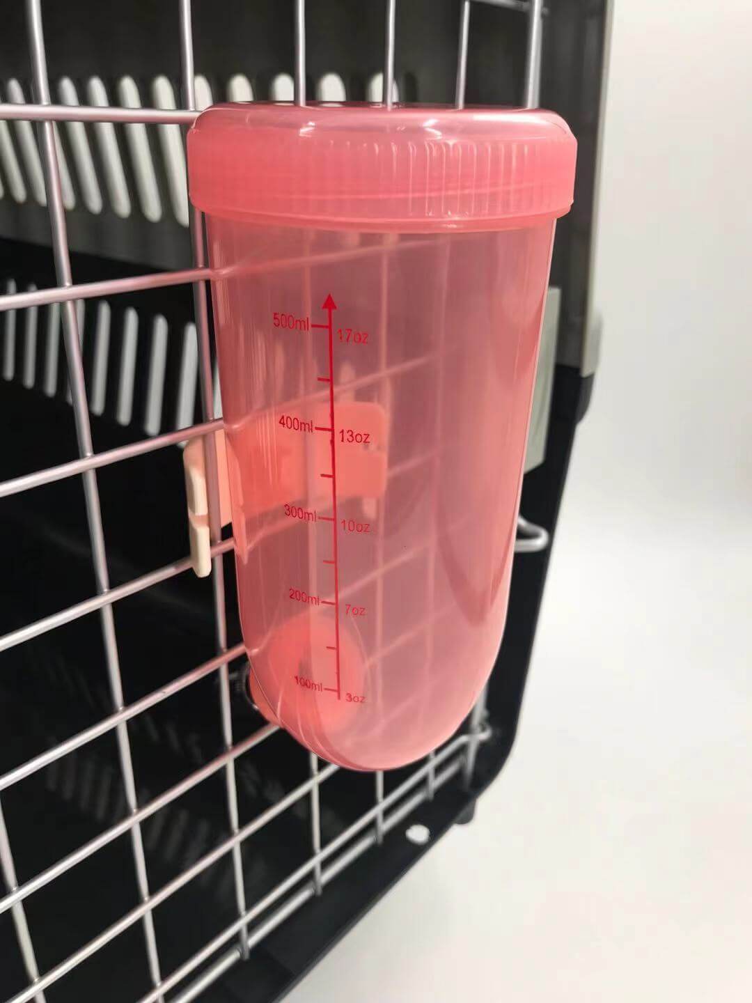 Pink 500ml hanging water bottle for pets, ideal for dogs, cats, hamsters and rabbits, fits securely in pet carriers.