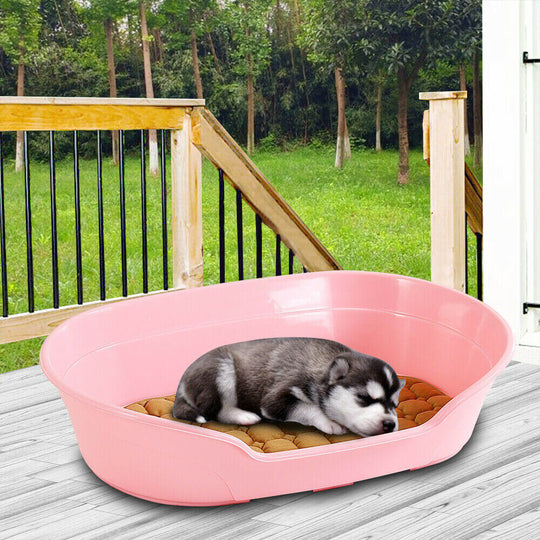 Small plastic pink pet bed with a cozy cushion, perfect for dogs to rest and sleep comfortably outdoors.