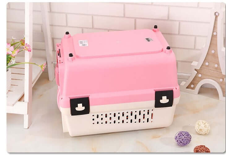 Lightweight pink portable pet carrier, ideal for travel with small dogs and cats, featuring vent slots and secure locks.